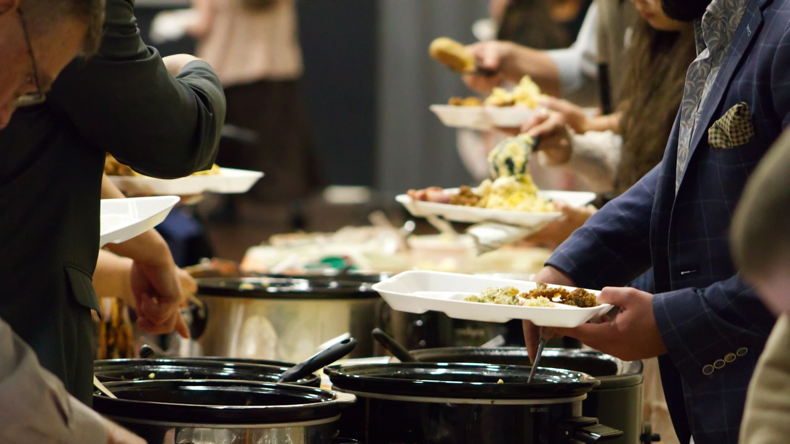 Potluck ideas in action: guests serving themselves from a line of slow cookers