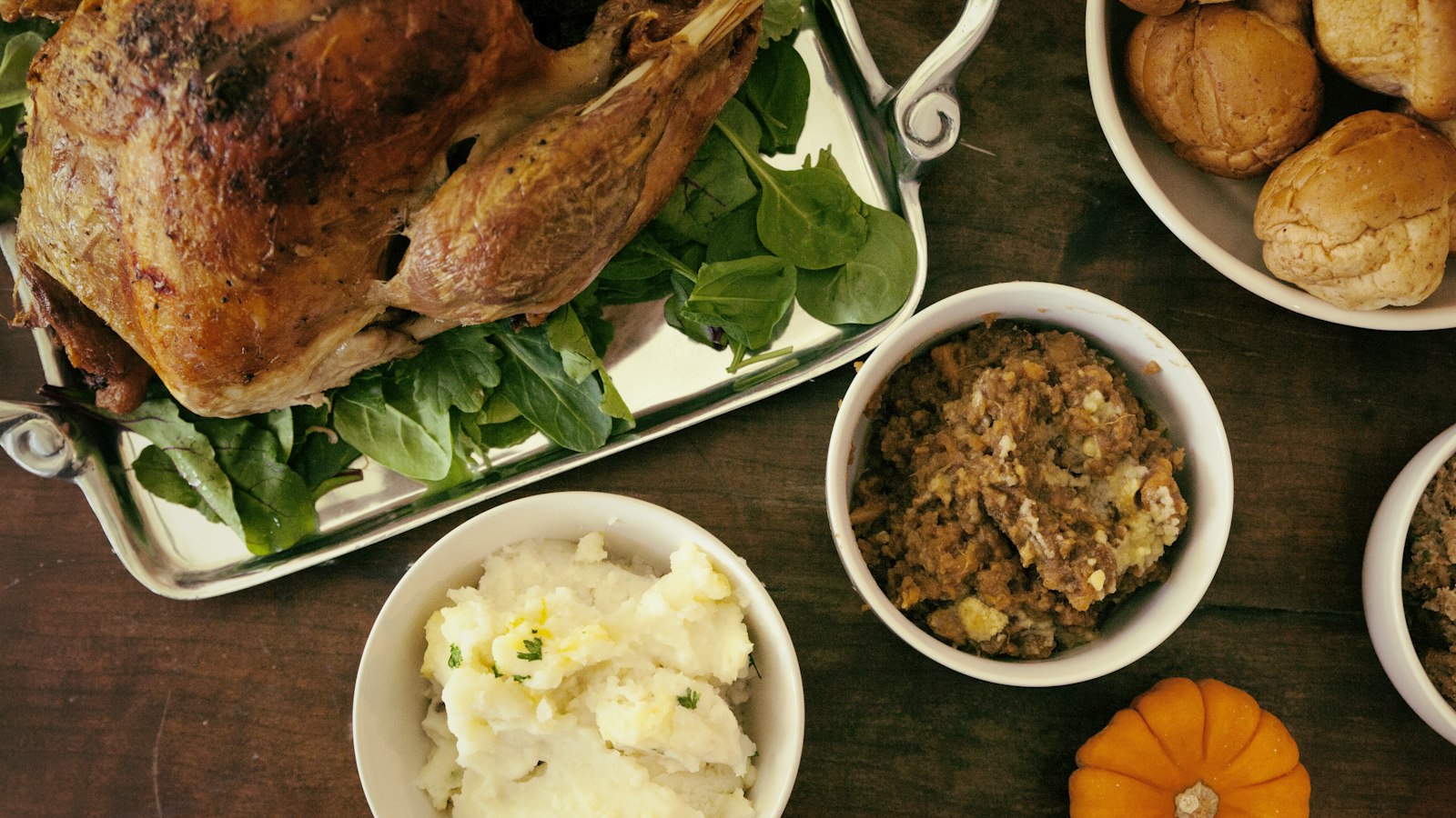 Thanksgiving potluck spread with turkey, mashed potatoes, stuffing and rolls